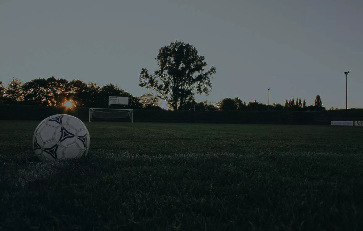 Un balón en el césped de un campo de fútbol al atardecer